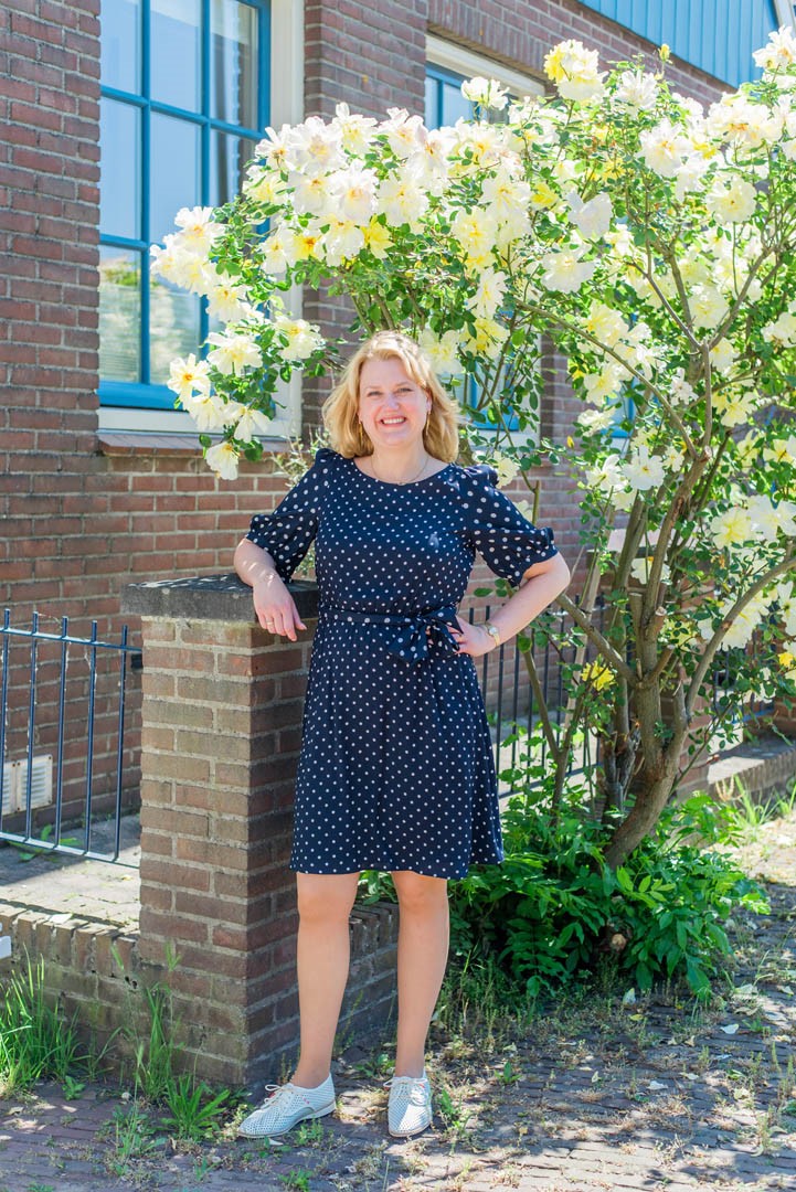 Foto Staand Buiten Voor Bloesemstruik Met Blauwe Polkadot Jurk